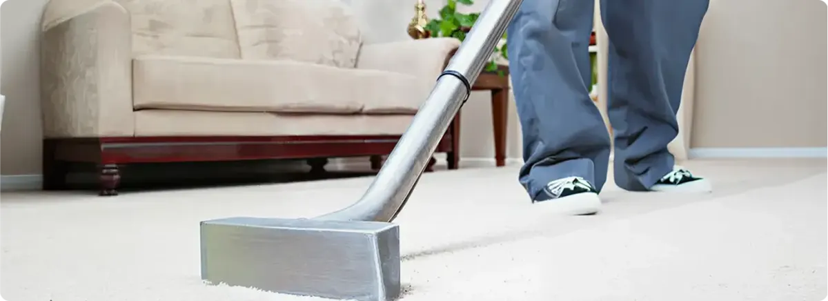 Carpet cleaning technician using a hot-water extraction wand on a light-colored carpet in a living room, El Paso, TX.