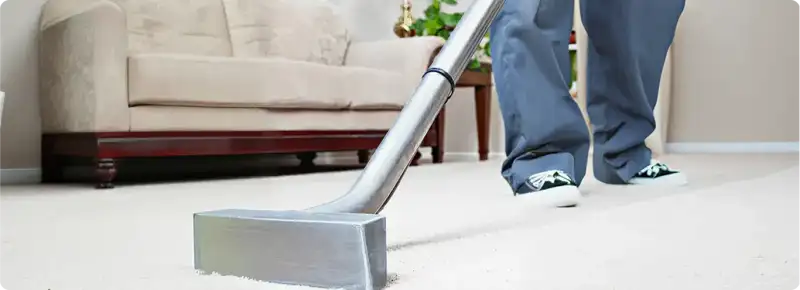 Carpet cleaning technician using a hot-water extraction wand on a light-colored carpet in a living room, El Paso, TX.