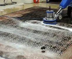 Professional rug cleaning with a rotary floor machine and shampoo foam, deep-cleaning an area rug, in El Paso, TX.